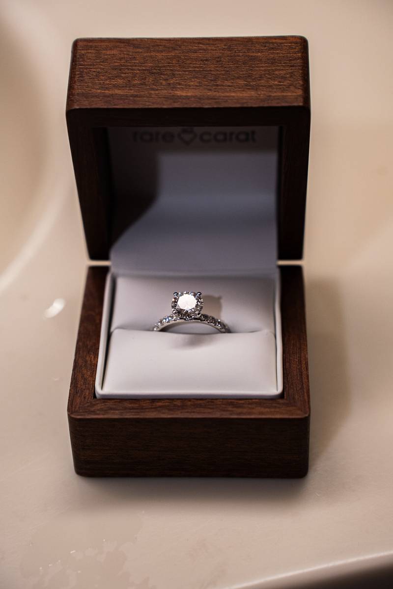 A diamond engagement ring in an open wooden ring box