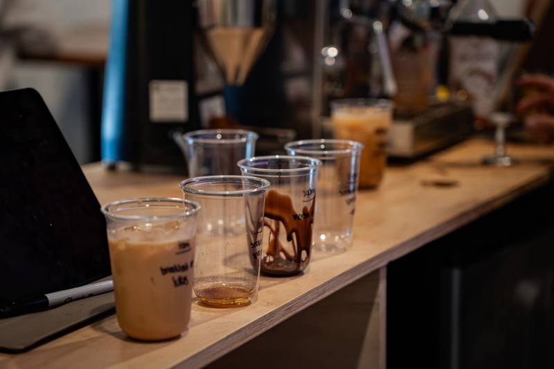 Iced coffee drinks lined up on a wooden bar at a coffee pop-up