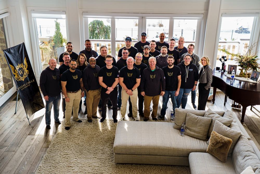 A group of about thirty people posed together in a bright living room