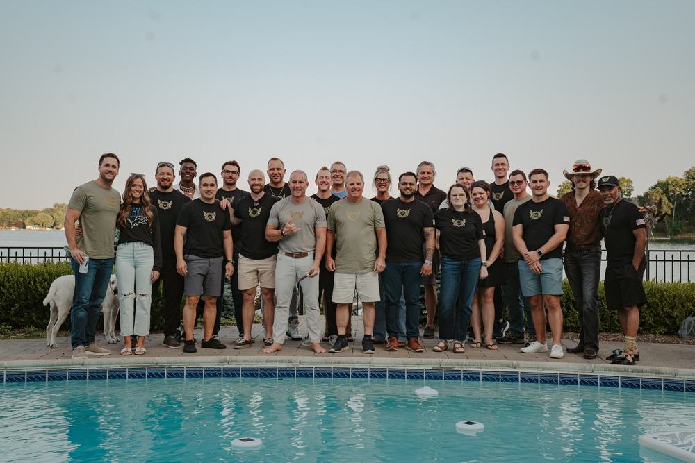 A group stands along the edge of a backyard pool at dusk