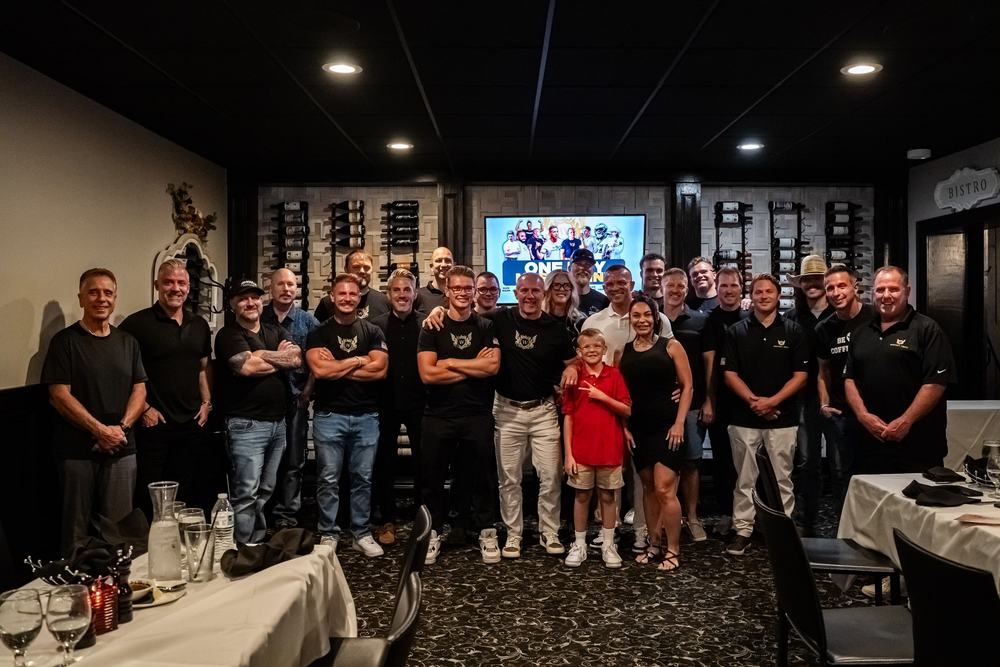 A large group poses between dining tables in a restaurant private room