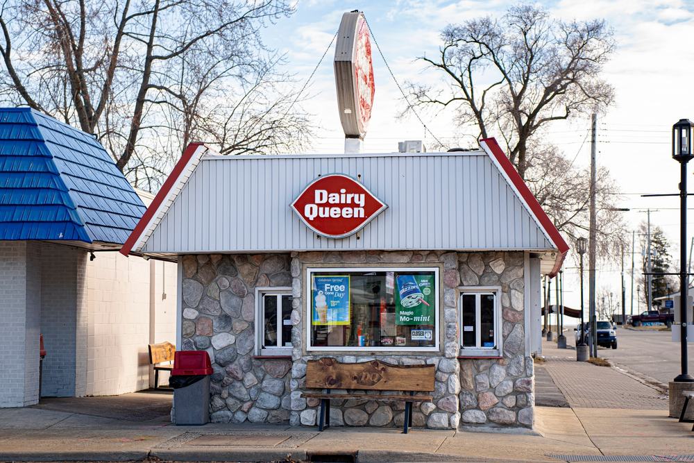 A small stone Dairy Queen walk-up with its red sign on a clear winter day