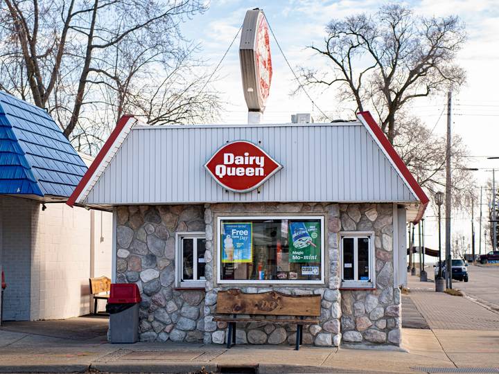 A small stone Dairy Queen walk-up with its red sign on a clear winter day