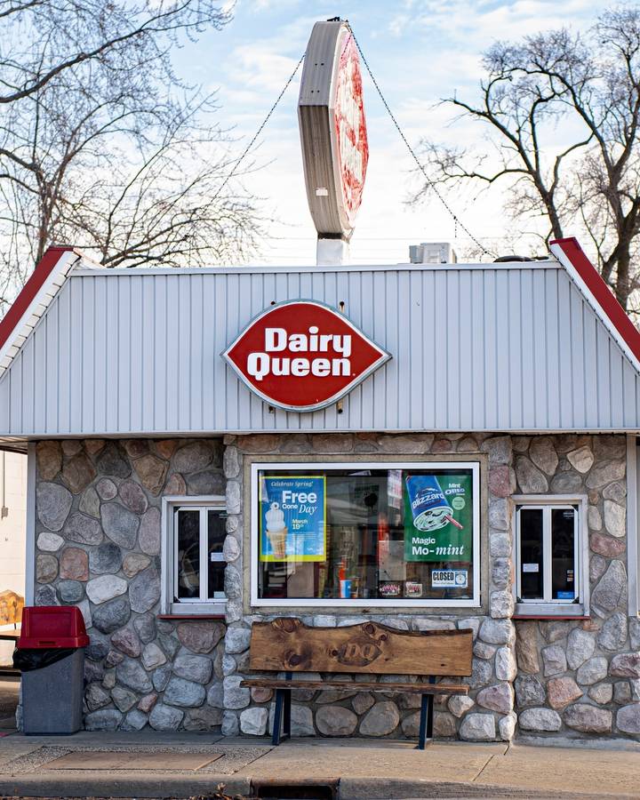 A small stone Dairy Queen walk-up with its red sign on a clear winter day